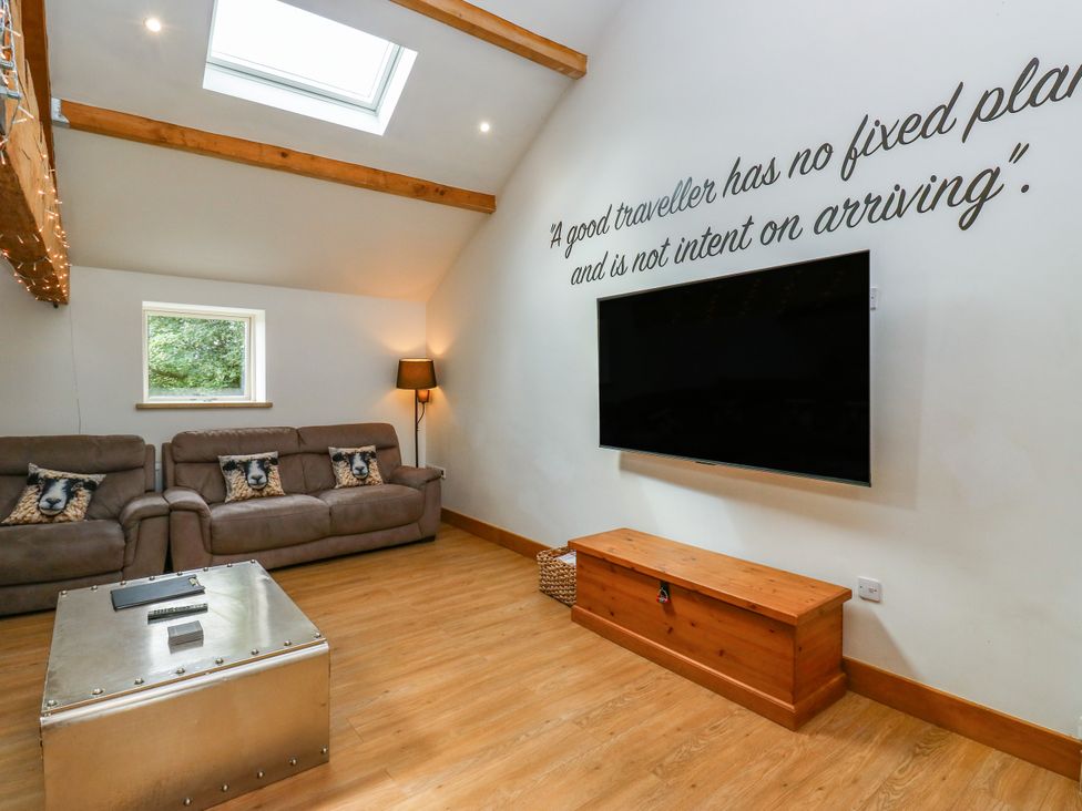 A living room with a sofa and television at Upper House Barn in Delph
