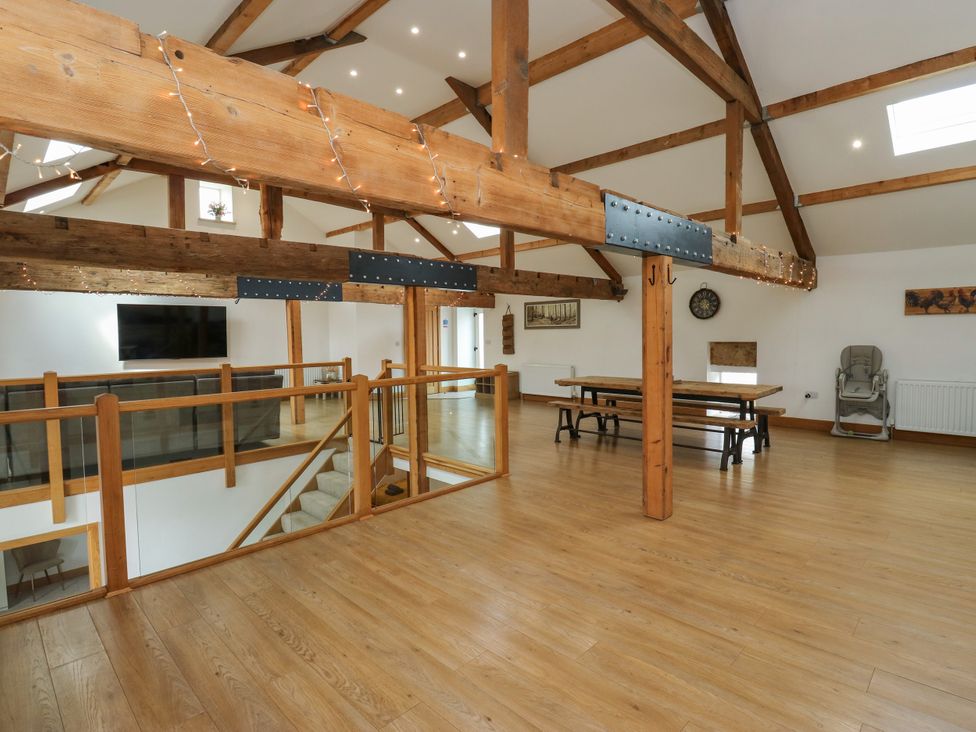A loft space with wooden beams and a large table at Upper House Barn (Saddleworth) Delph