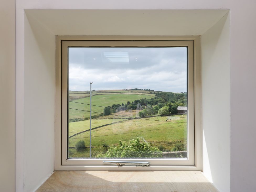 A view from a window showing fields and hills at Upper House Barn (Saddleworth) Delph