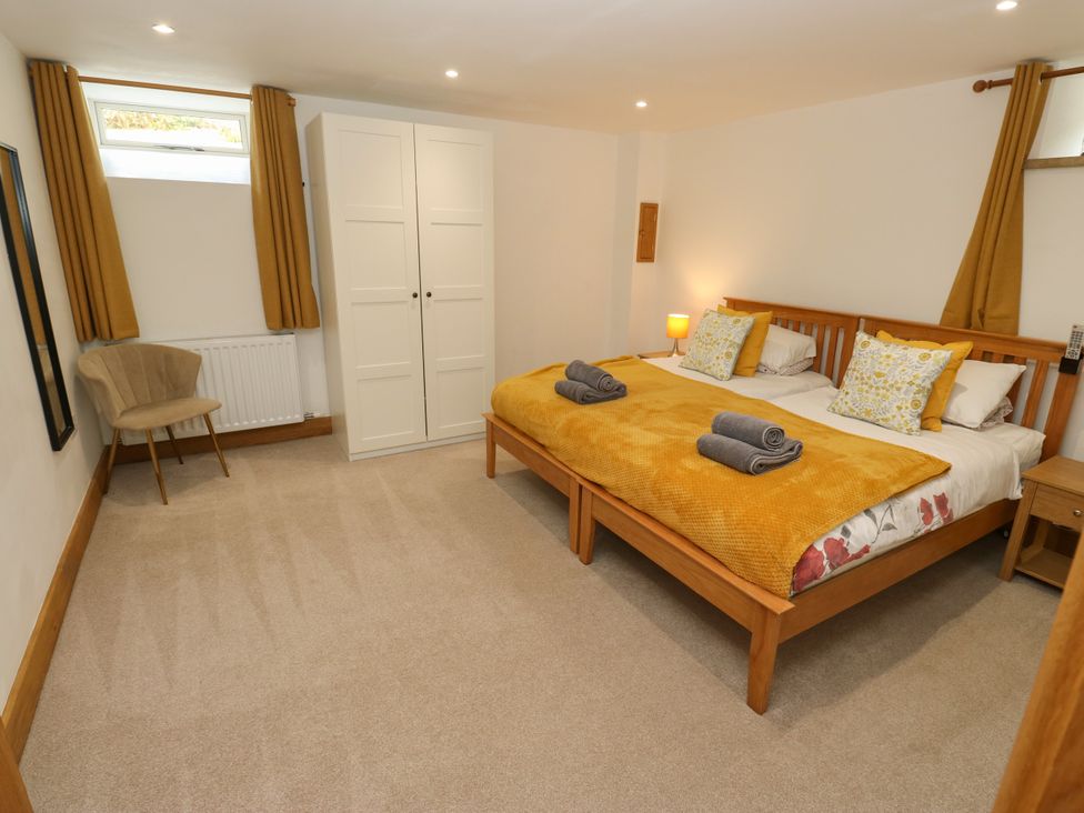 A bedroom with two beds and a wardrobe at Upper House Barn in Delph
