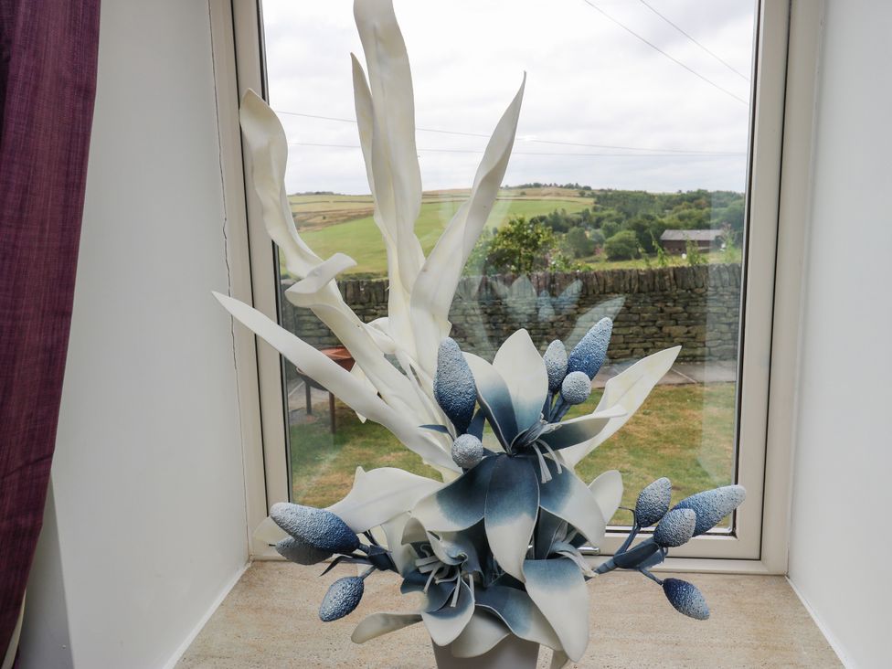 A flower arrangement in a vase in front of a window at Upper House Barn (Saddleworth) Delph