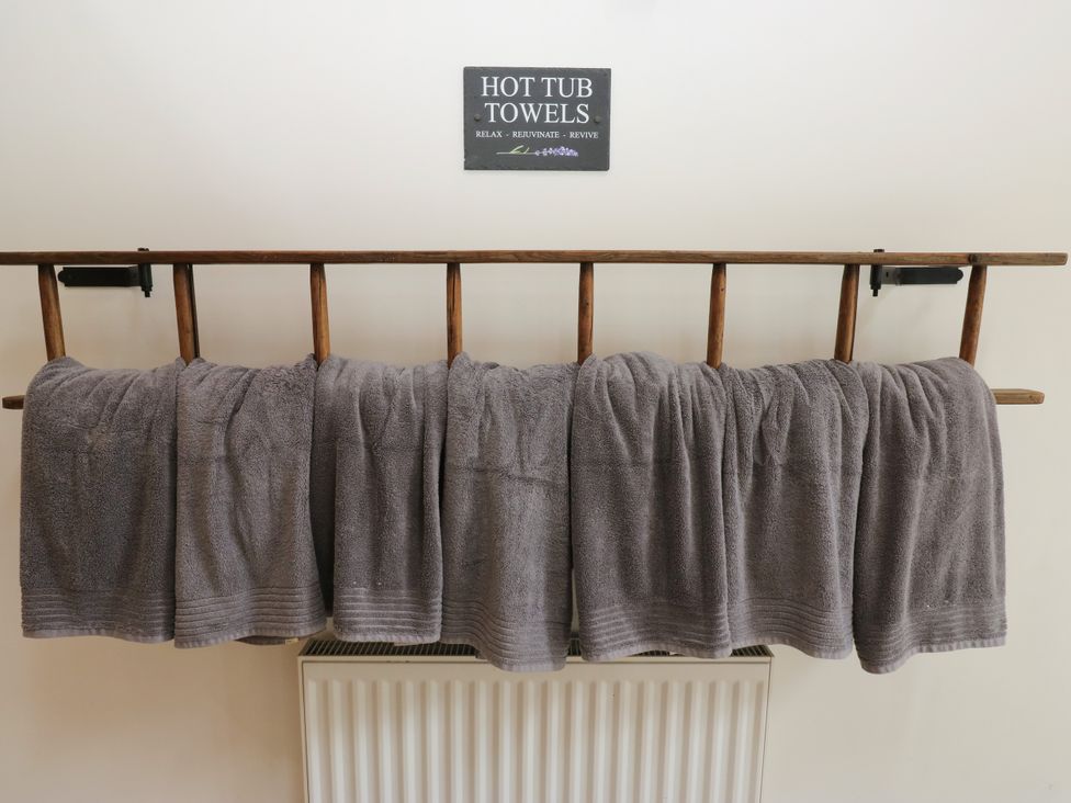 A rack with towels and a sign in a bathroom at Upper House Barn (Saddleworth) Delph