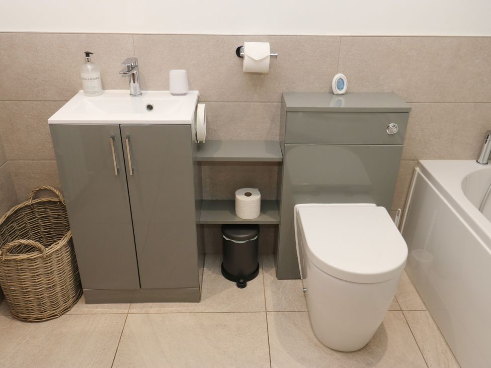 A bathroom with sink, toilet, and storage cabinet at Upper House Barn (Saddleworth) in Delph