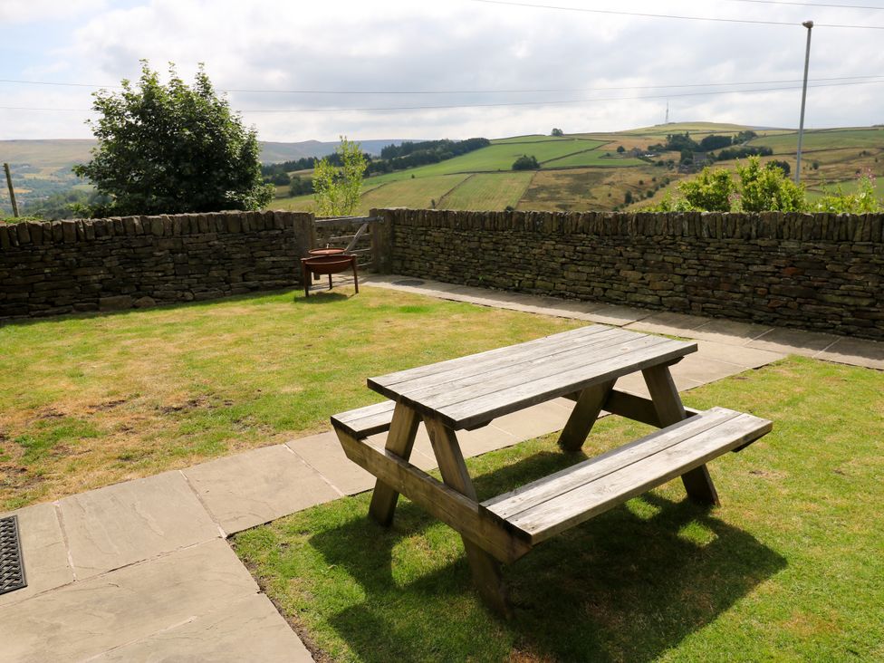 A garden with a picnic table and fire pit at Upper House Barn (Saddleworth) Delph