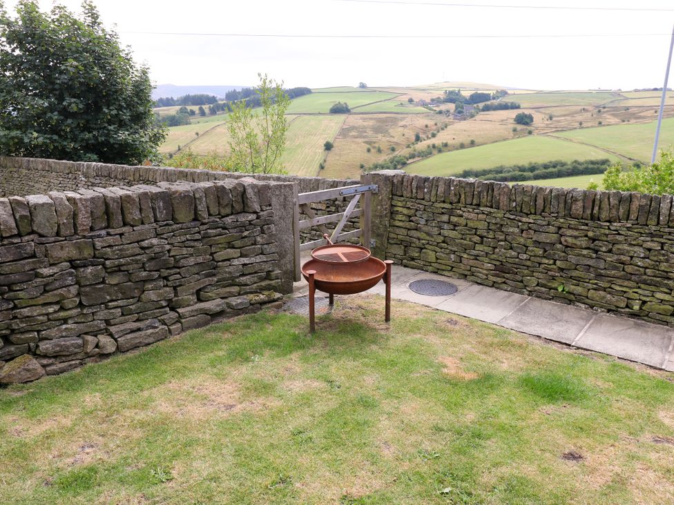 A garden with a fire pit and stone wall at Upper House Barn (Saddleworth) Delph