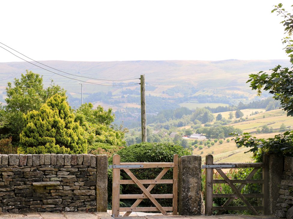 A view of a gate and stone wall overlooking a landscape at Upper House Barn (Saddleworth) Delph