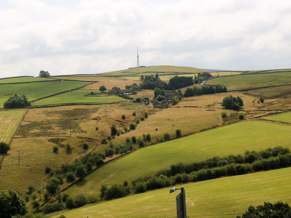 A landscape featuring fields and a farmhouse near a communications tower at Upper House Barn (Saddleworth) Delph