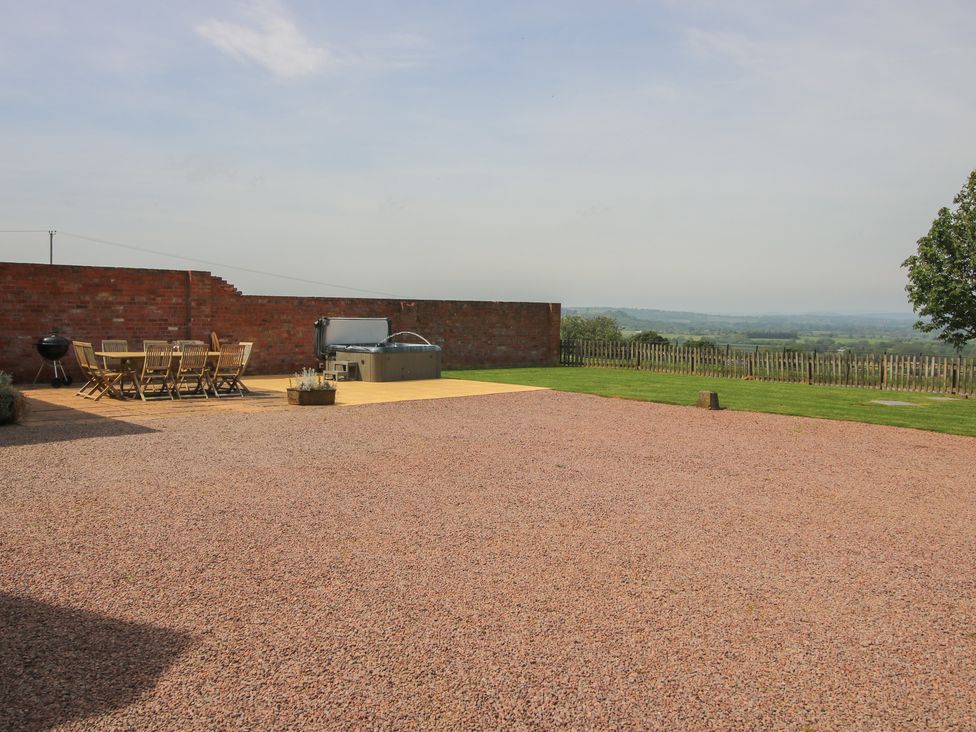 An outdoor area with a table, chairs, and a hot tub at Hunters Moon, Tenbury Wells