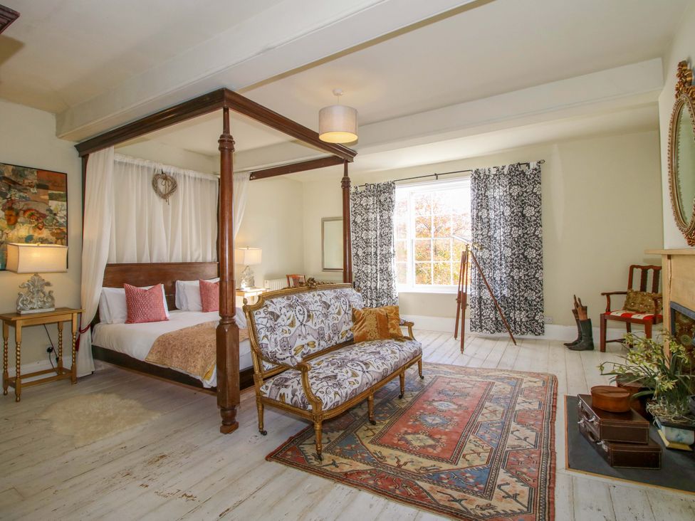 A bedroom with a canopy bed and sitting area at Hilltop House in Tenbury Wells
