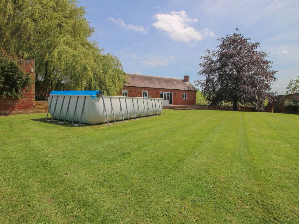 A garden with a swimming pool and trees at Hilltop House in Tenbury Wells