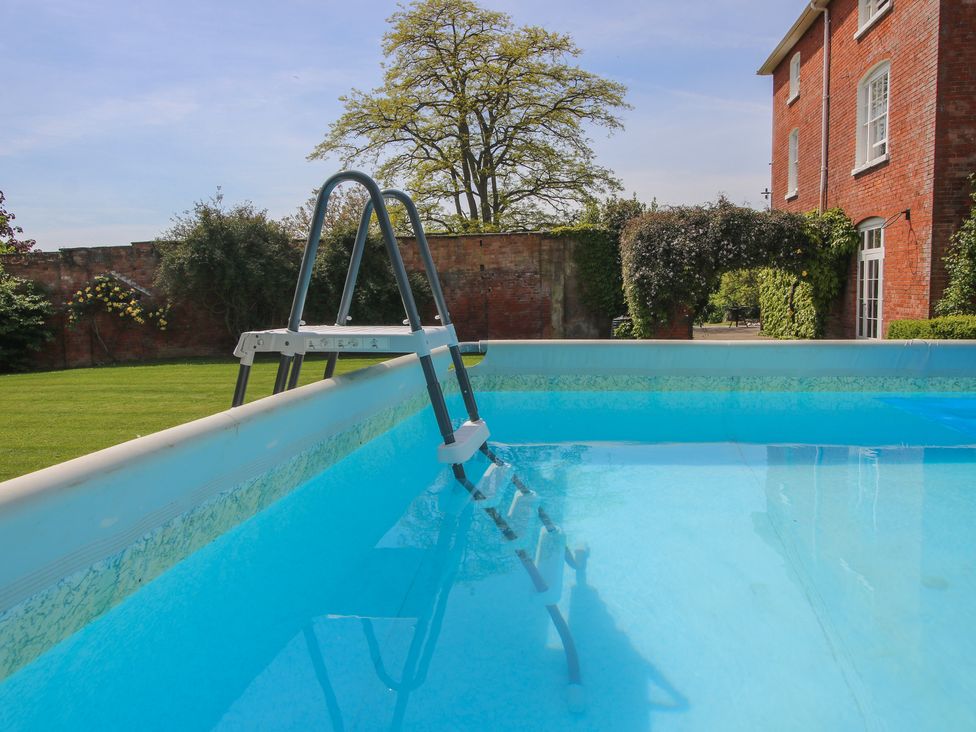 A pool with a ladder and grass area at Hilltop House Tenbury Wells