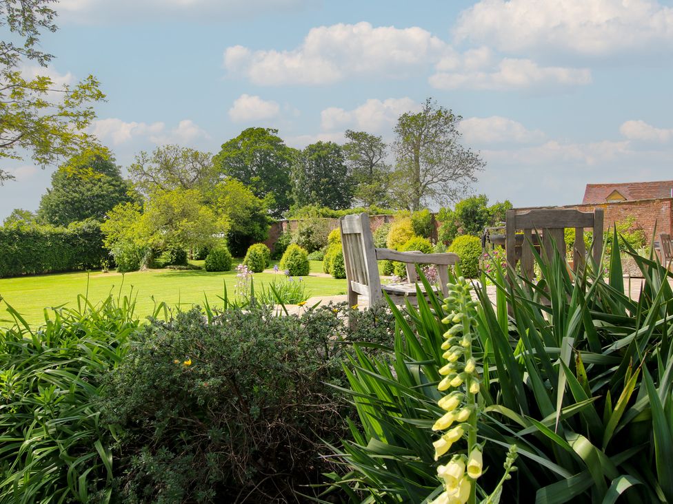 A garden with a wooden bench and green grass at Hilltop House in Tenbury Wells