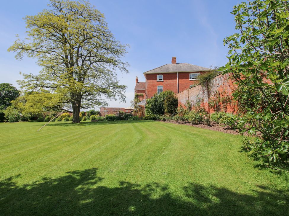 A garden with a tree and house at Hilltop House Tenbury Wells