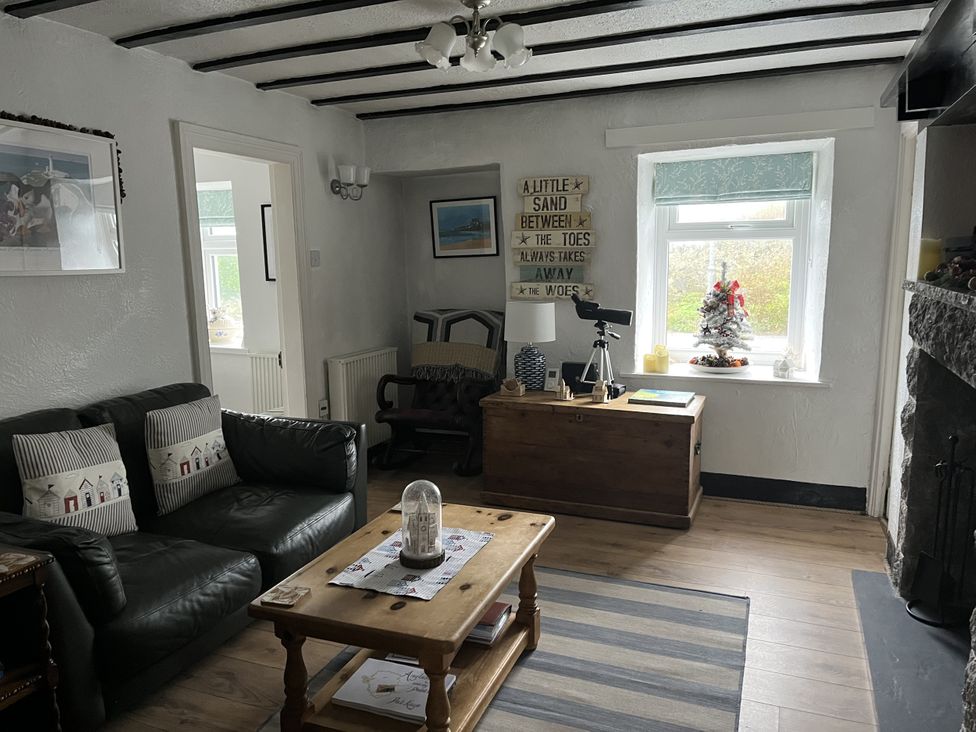 A living room with a sofa, coffee table, and armchair at Tyddyn Serri in Rhosneigr