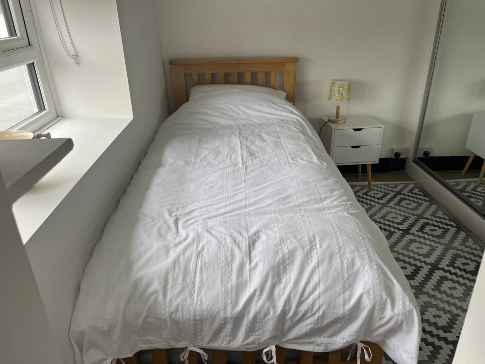 A bedroom with a single bed and a bedside table at Tyddyn Serri in Rhosneigr