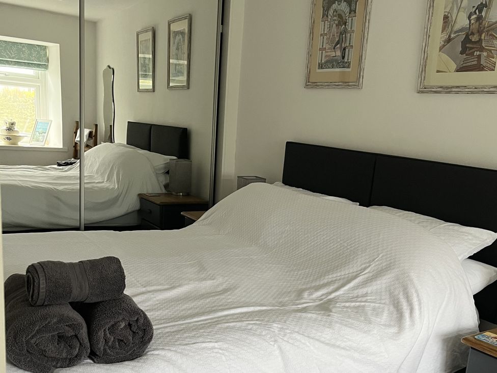 A bedroom with a bed and towels on the side at Tyddyn Serri in Rhosneigr