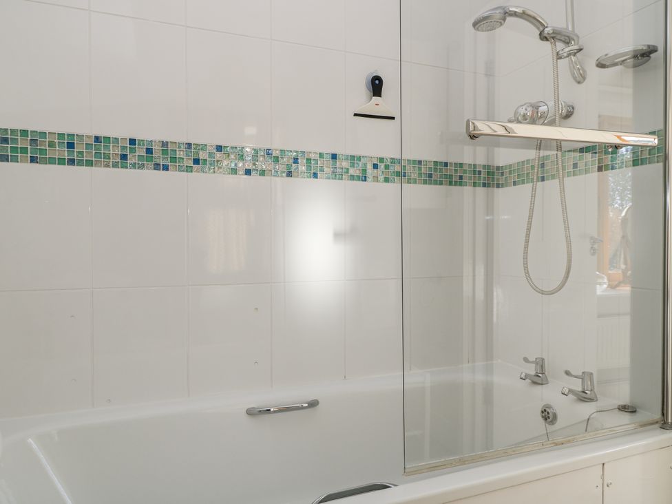 A bathtub with a shower and colorful tiles at Keepers Cottage in West Knoyle