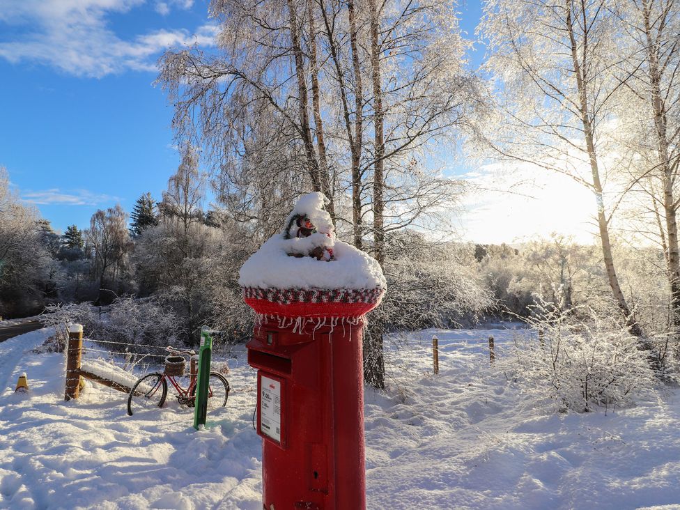 A post box covered in snow with a bicycle nearby in Aviemore