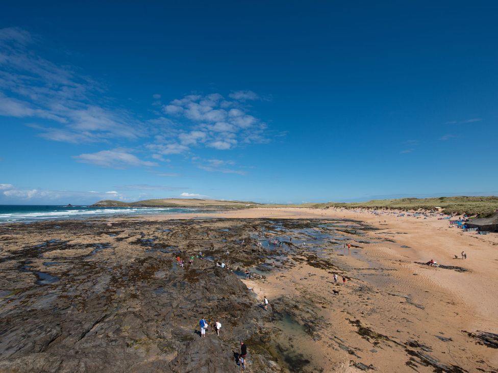 A beach with people and rocks at Beachcomber in Padstow