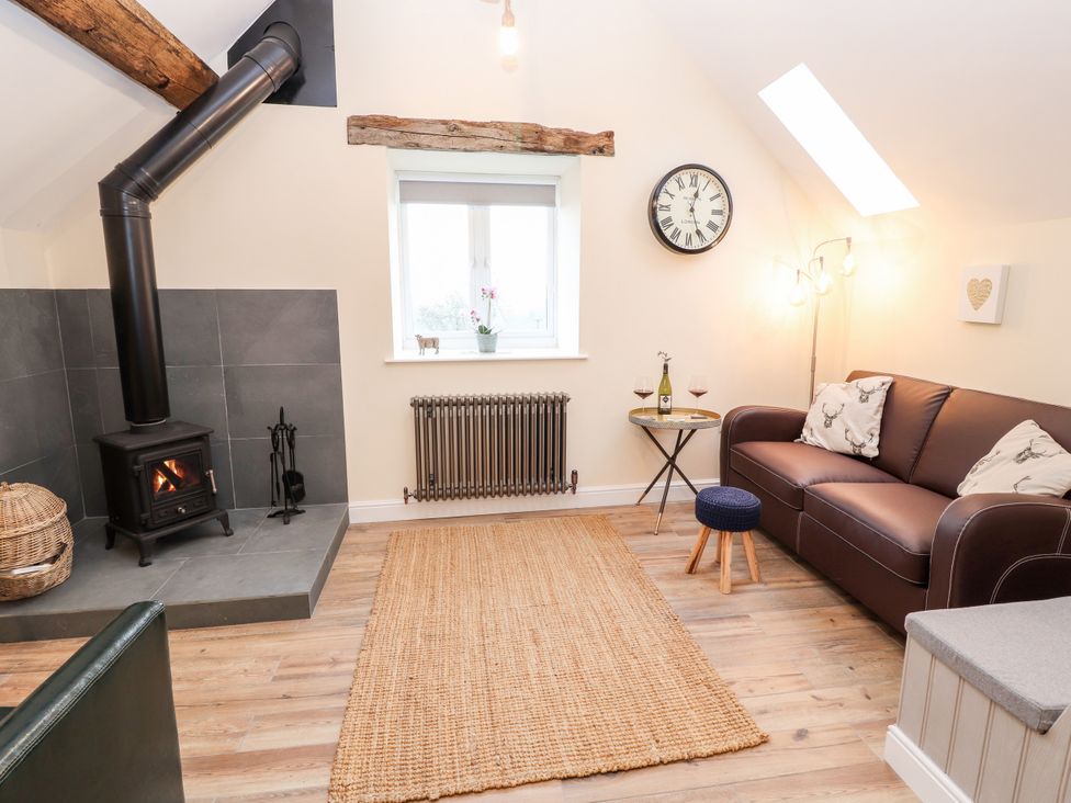 A living room with a stove and sofa at Stabl, Plas Moelfre Hall Barns, Moelfre near Llanrhaeadr-Ym-Mochnant
