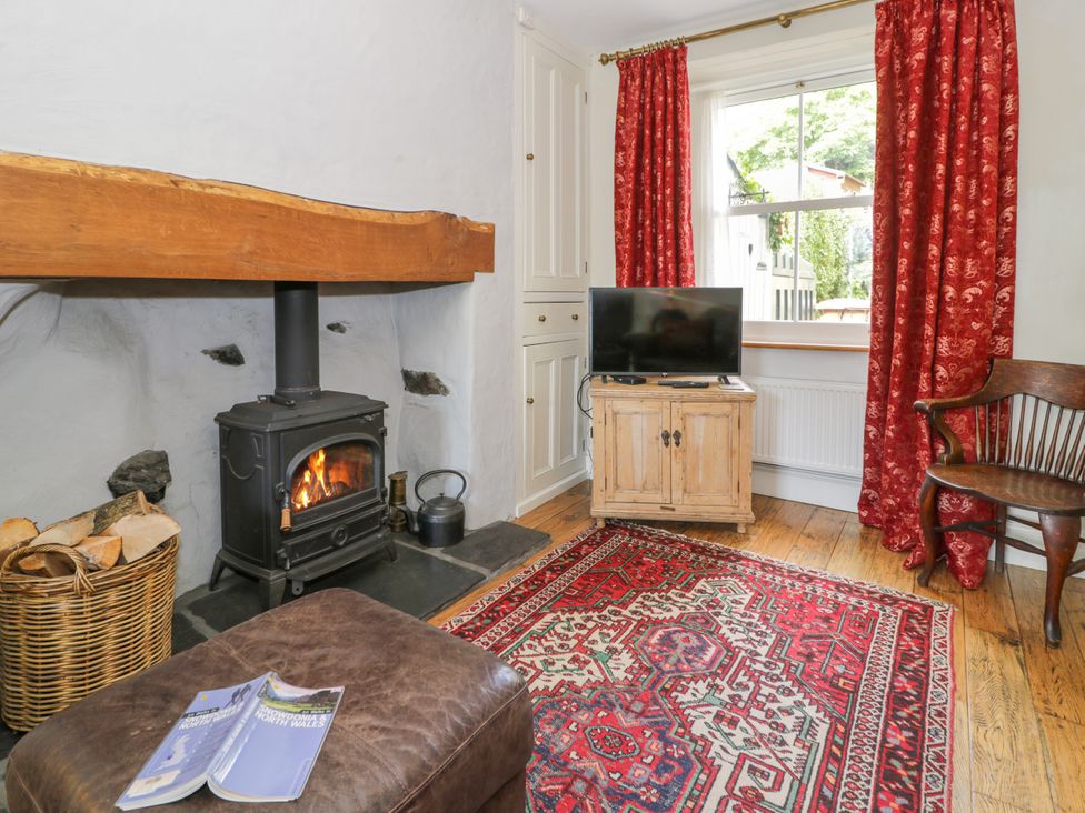 A living room with a stove and wooden furniture at Sygun View Beddgelert