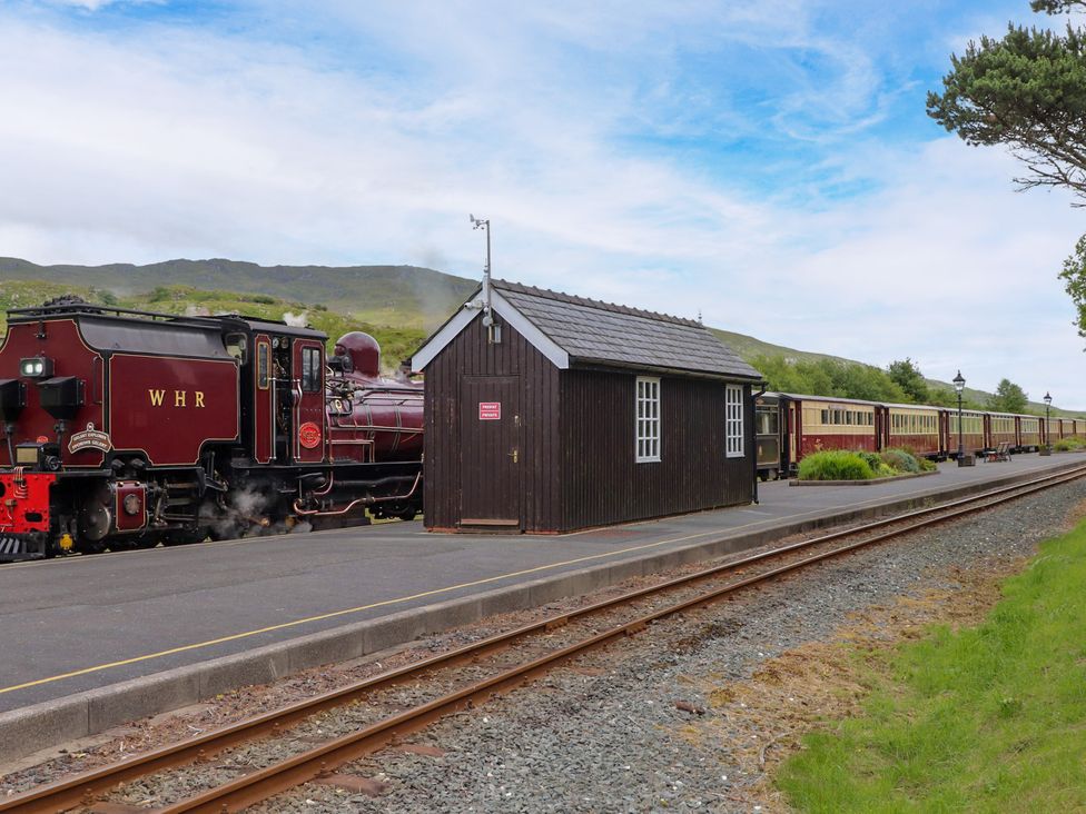 A steam train at a station with a wooden shed at Sygun View Beddgelert