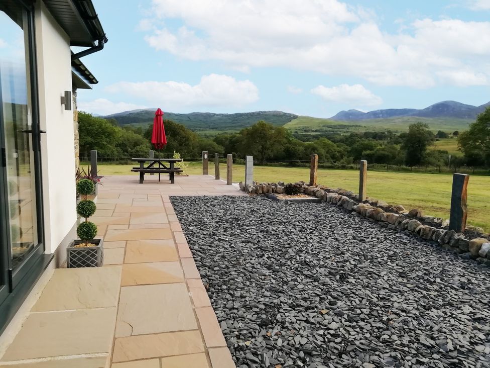 A patio with a picnic table and an umbrella at Cartref Trawsfynydd