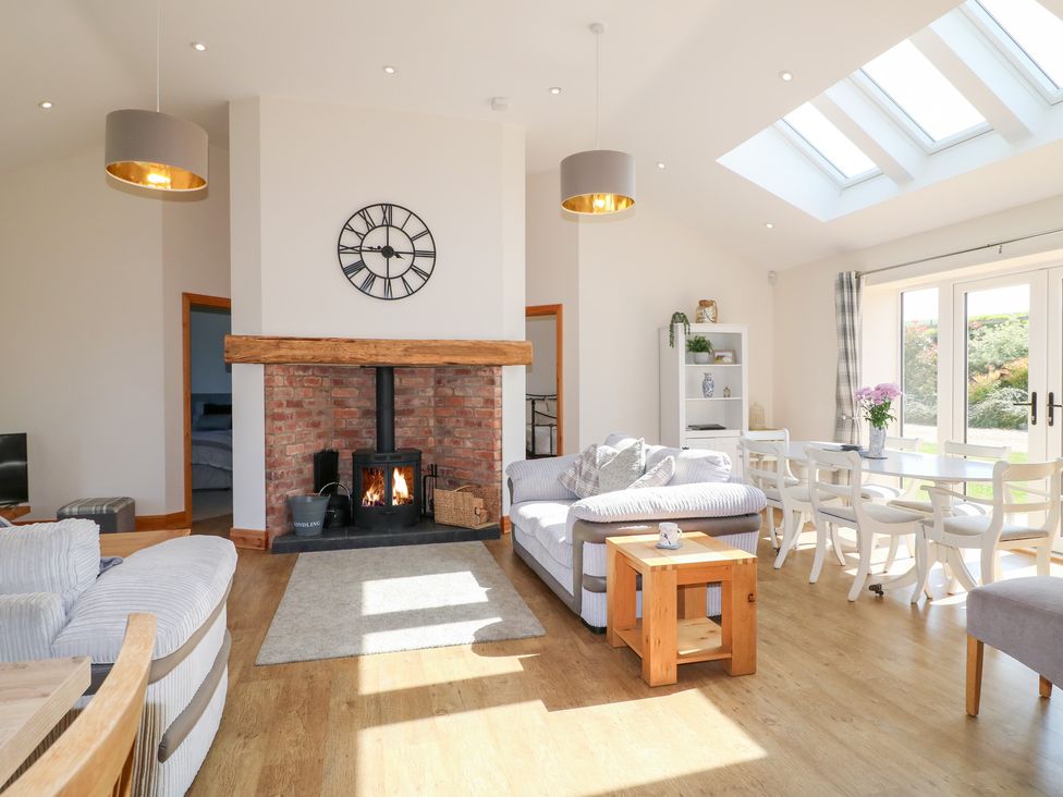 A living room with a fireplace and dining table at Mandarin Cottage in Melton Mowbray