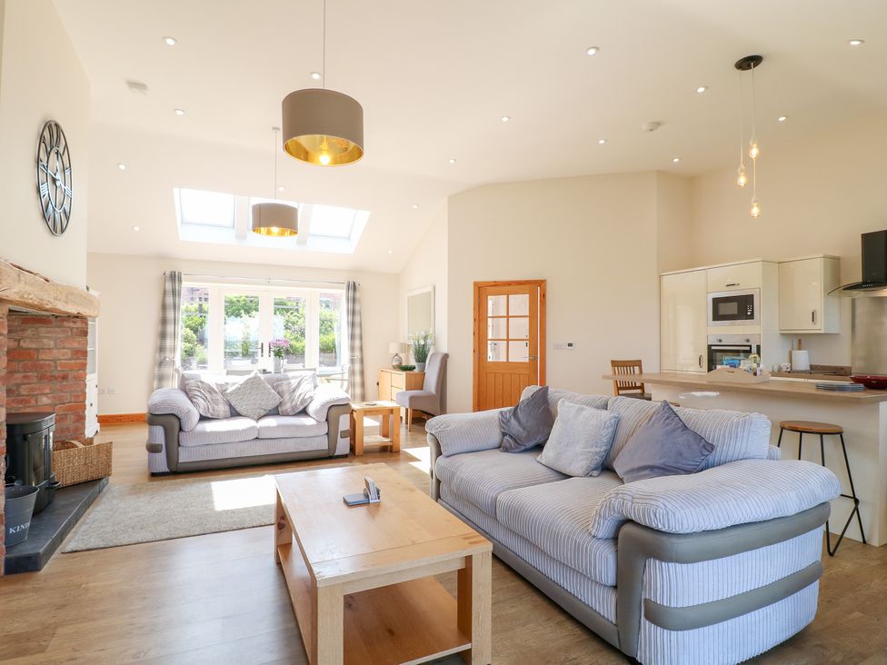 A living room with seating and a kitchen area at Mandarin Cottage in Melton Mowbray