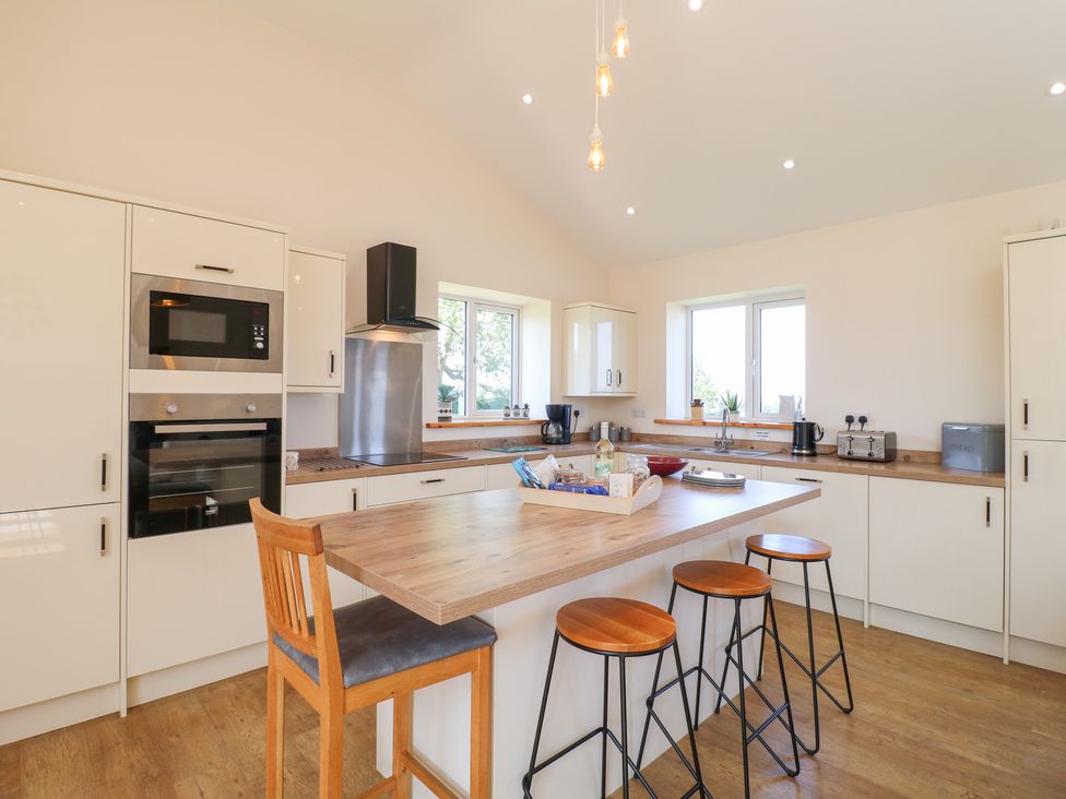 A kitchen with appliances and seating at Mandarin Cottage in Melton Mowbray