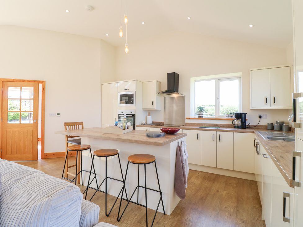 A kitchen with bar stools and appliances at Mandarin Cottage in Melton Mowbray