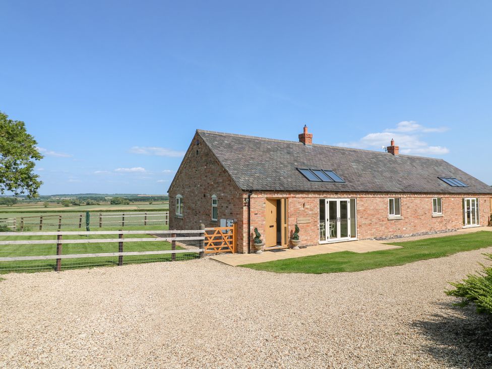 An exterior view of a house with a driveway and grass at Mandarin Cottage in Melton Mowbray