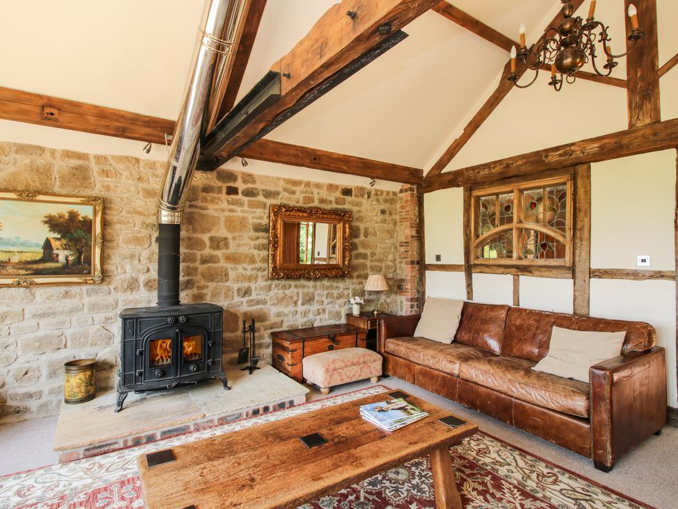 A living room with a sofa and a stove at Corn House in Cardington