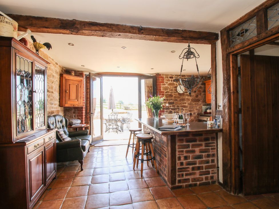 A kitchen with bar stools and a dining table at Corn House in Cardington