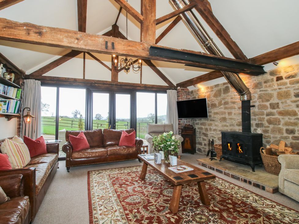 A living room with a fireplace and large windows at Corn House in Cardington