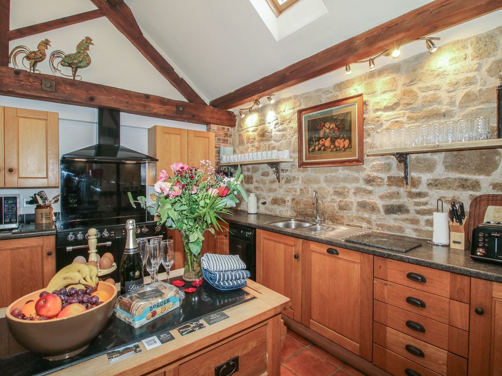 A kitchen with wooden cabinets and a fruit bowl at Corn House in Cardington