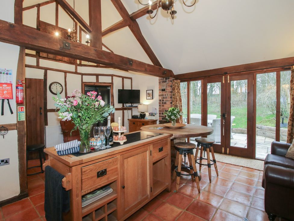 A kitchen with a kitchen island and bar stools at Corn House in Cardington
