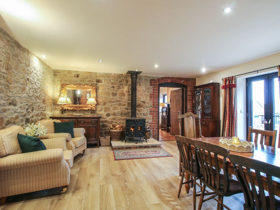 A living room with a fireplace and dining area at Corn House in Cardington