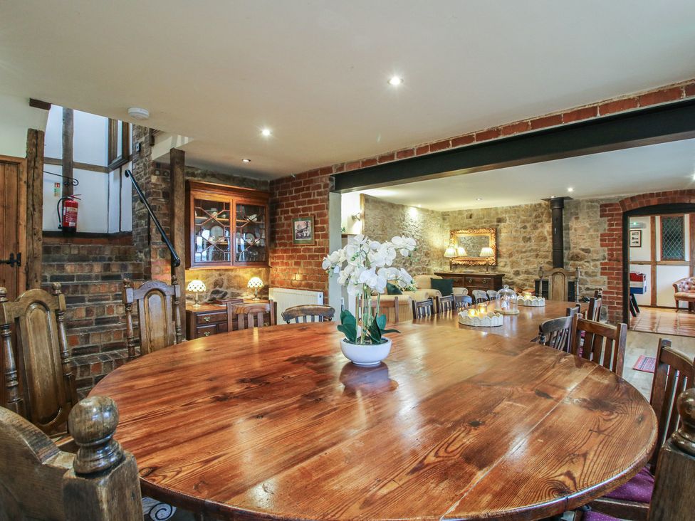 A dining room with a large table and flowers at Corn House in Cardington