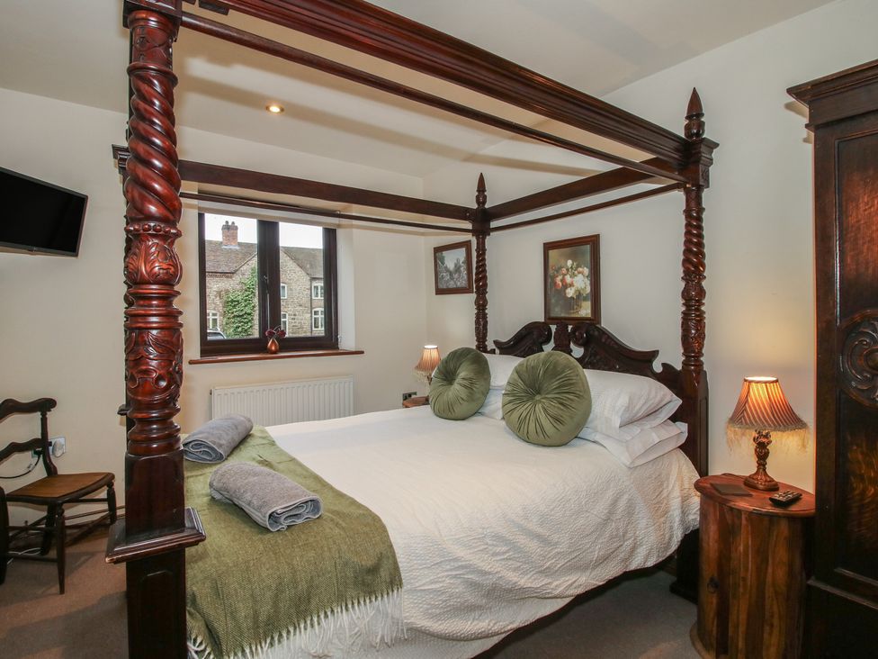 A bedroom with a four-poster bed and a television at Corn House in Cardington