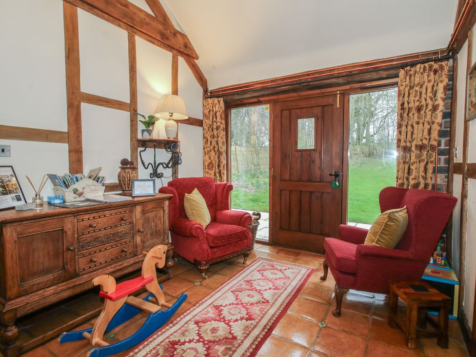 A snug with armchairs and a wooden cabinet at Corn House in Cardington