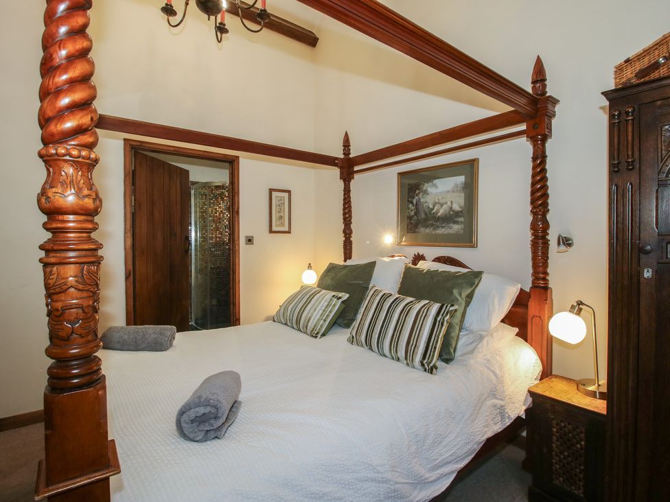 A bedroom with a four-poster bed and wall art at Corn House in Cardington