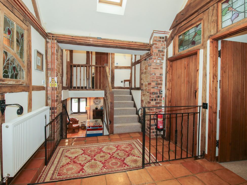 A hallway with stairs and stained glass windows at Corn House in Cardington
