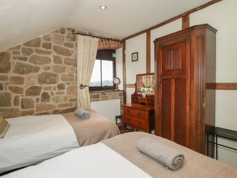 A bedroom with two beds and a wardrobe at Corn House in Cardington