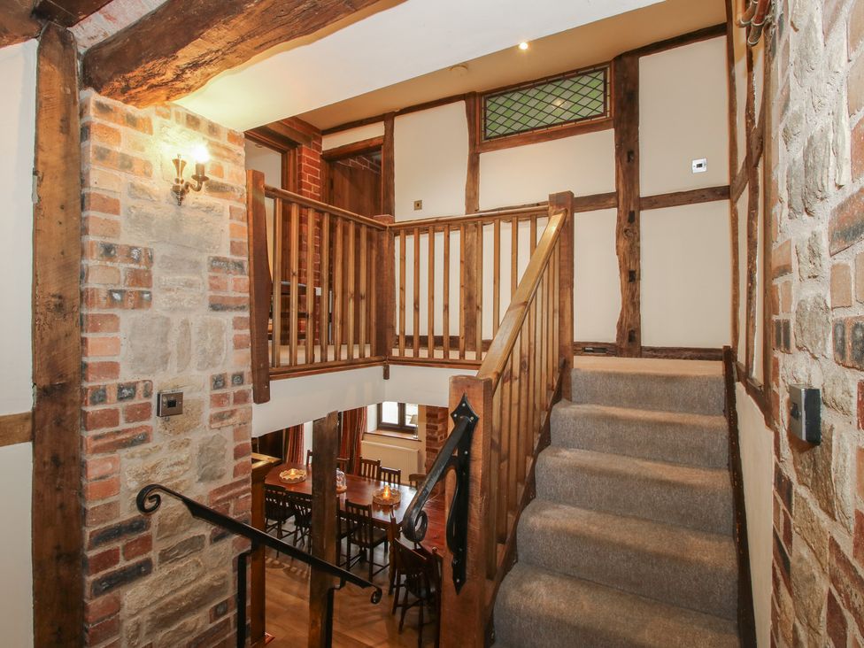 A staircase with wooden railing and brick wall at Corn House in Cardington