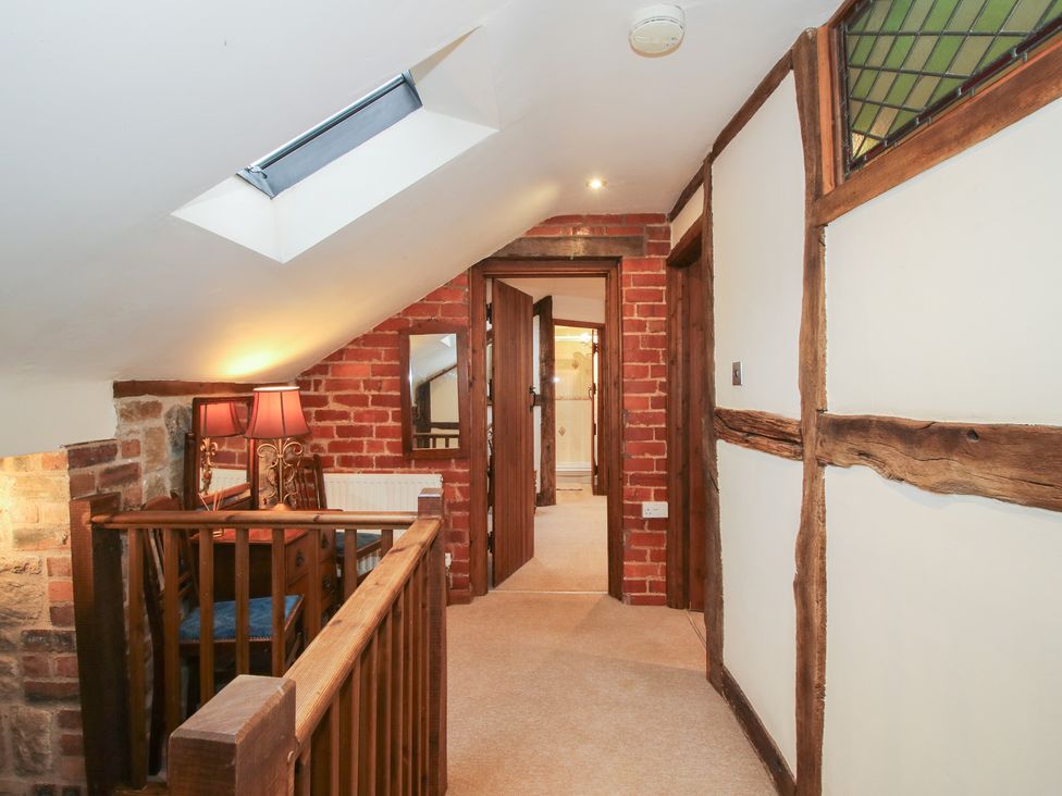 A hallway with a staircase and lamp at Corn House in Cardington