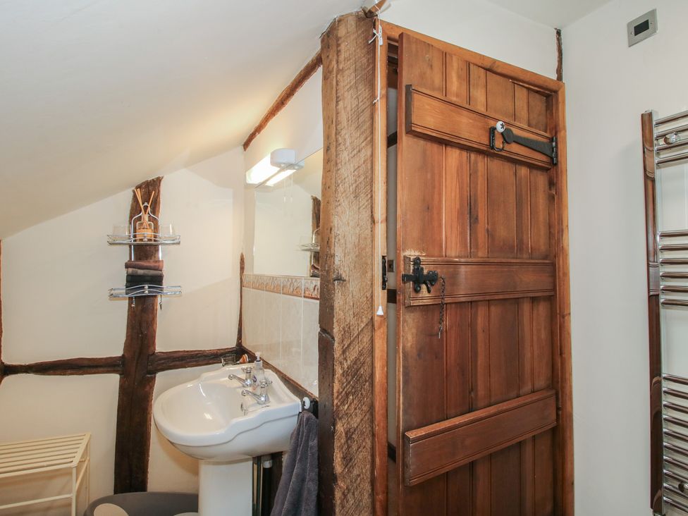 A bathroom with a sink, mirror, and wooden door at Corn House in Cardington