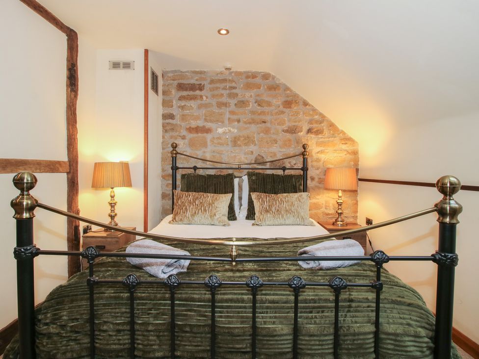 A bedroom with a bed and bedside lamps at Corn House Cardington