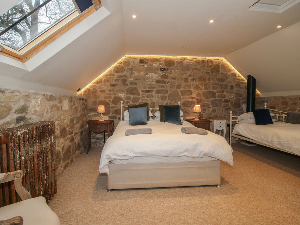 A bedroom with two beds and stone walls at Corn House in Cardington