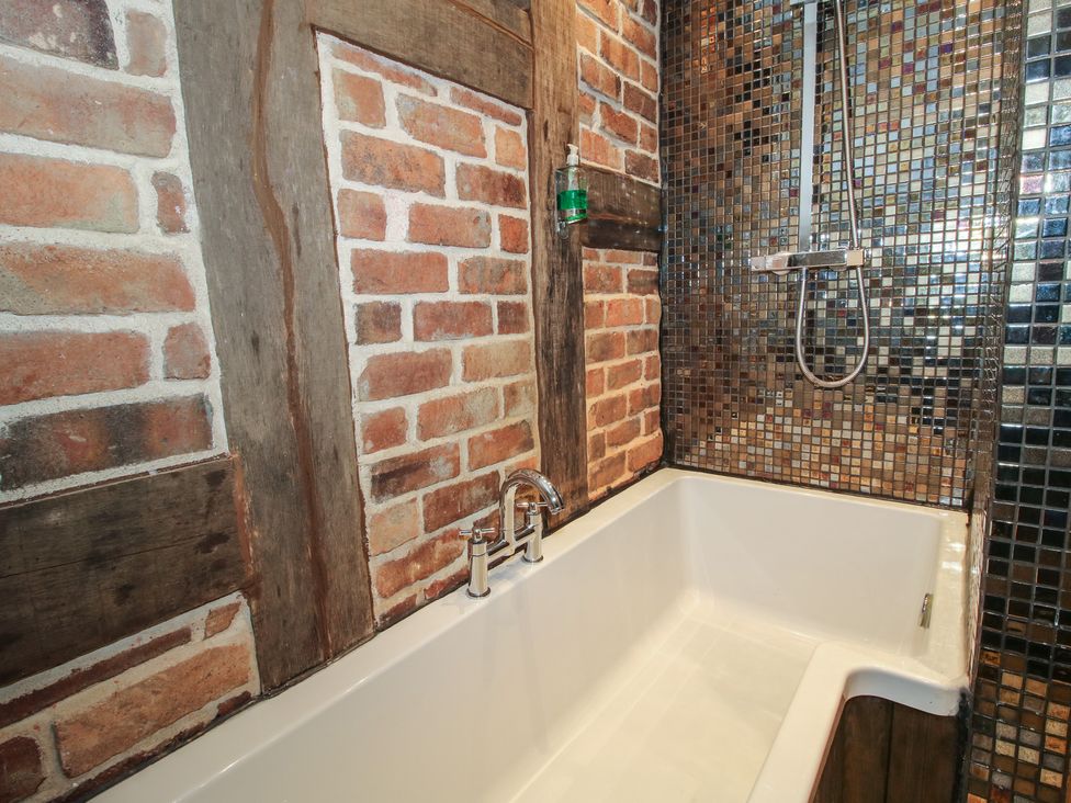 A bathroom with a bathtub and shower fixtures at Corn House in Cardington